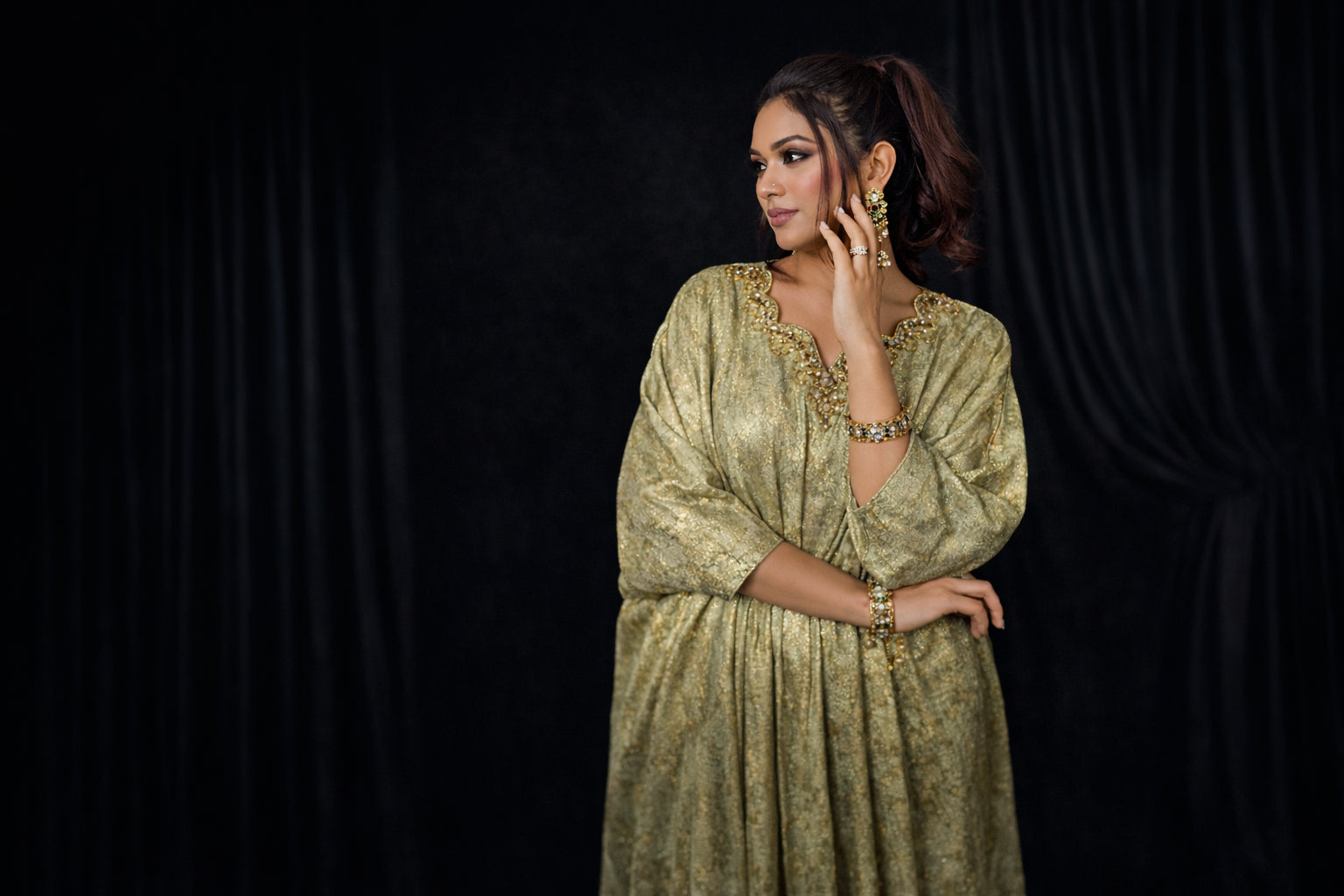 Woman wearing a green traditional outfit against a black background